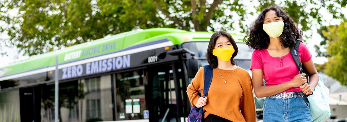 Two students walking away from AC Transit bus